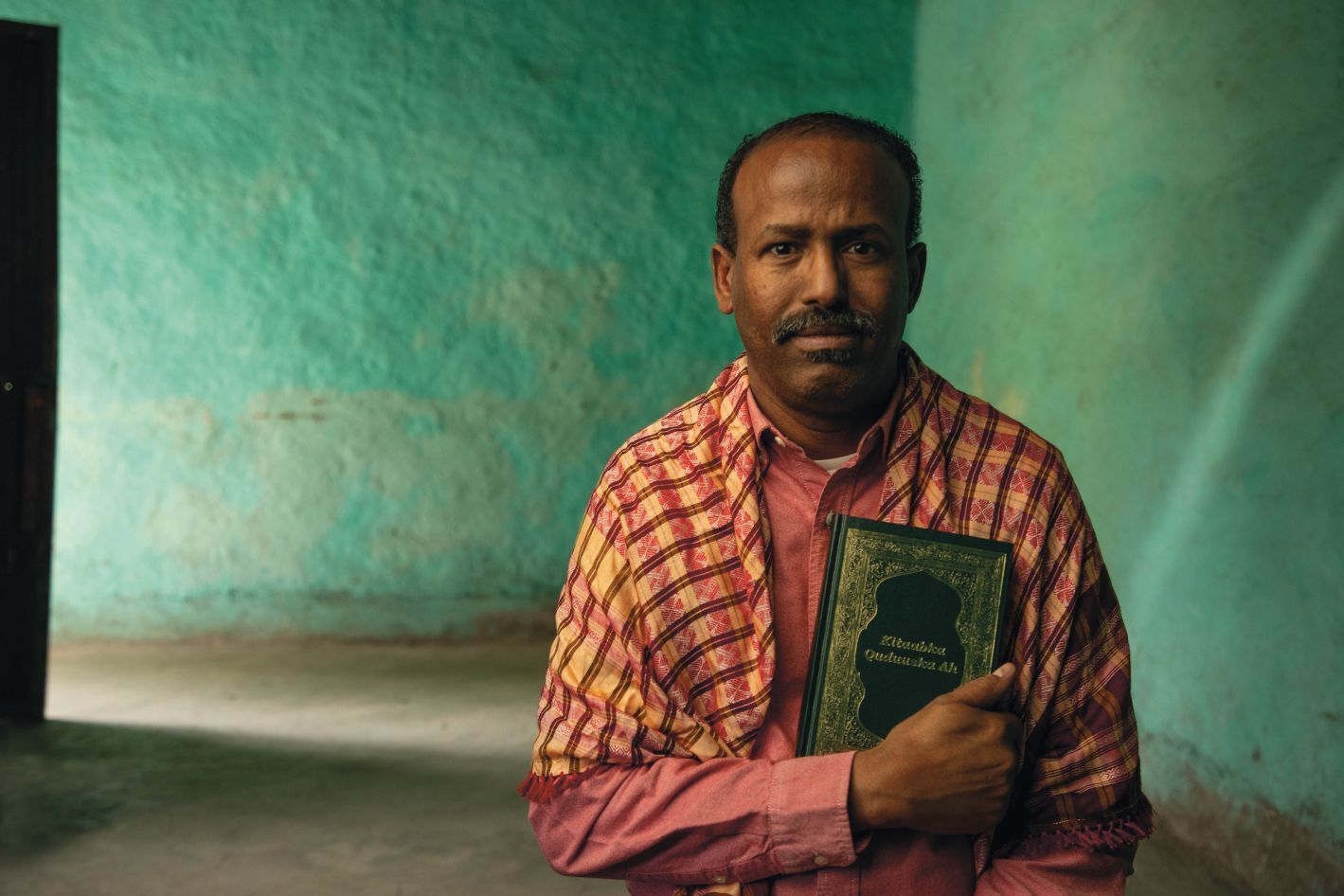 Moški v somalskem šalu drži Sveto pismo.