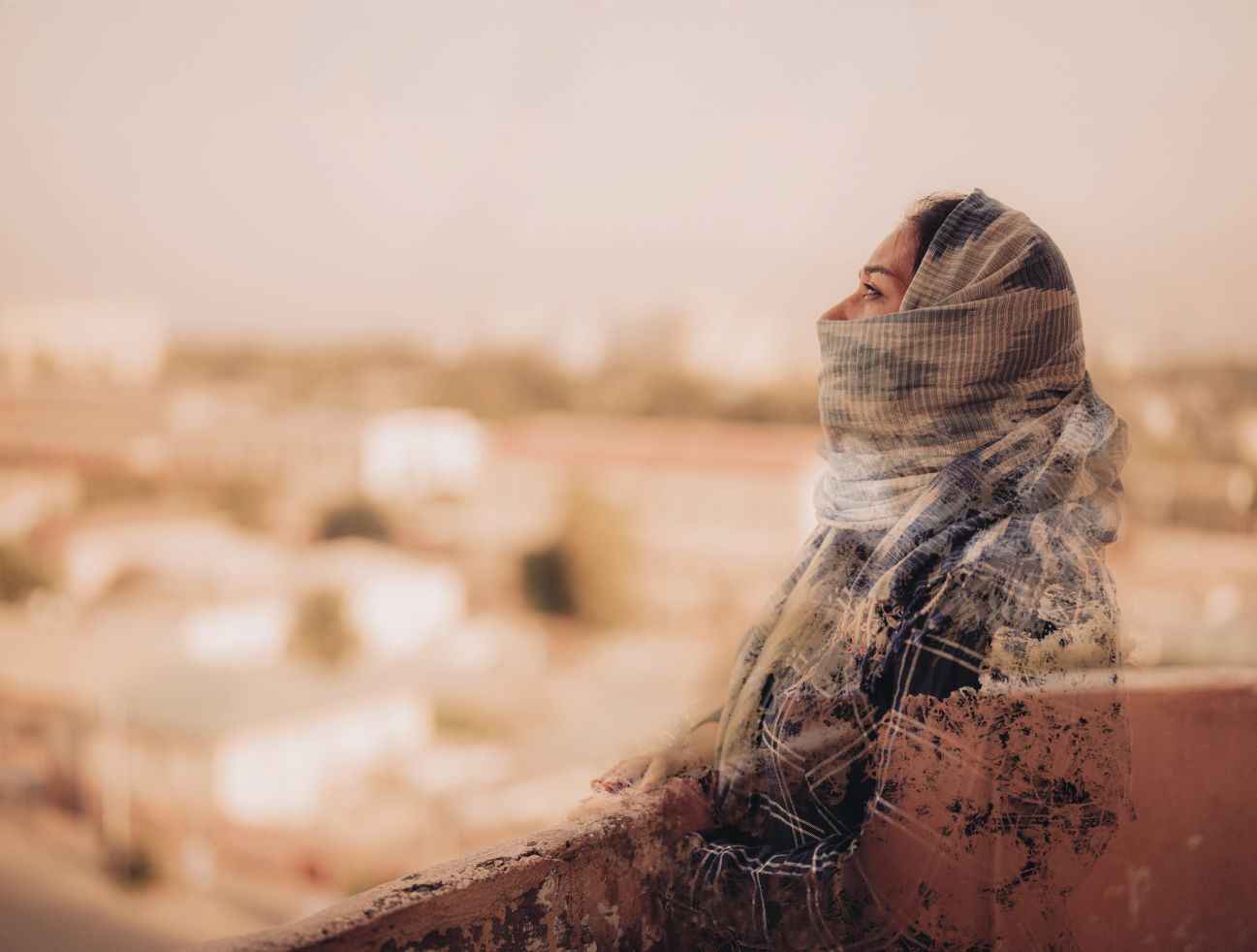 Ariana stoji na balkonu in gleda stran. Njeno telo je delno izbrisano.